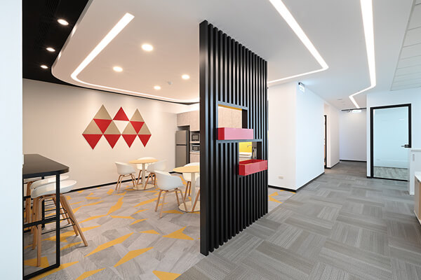 在空間規劃上，牆面以幾何造型拼貼與線性圖騰地毯，打造出明亮與活力的辦公氛圍。